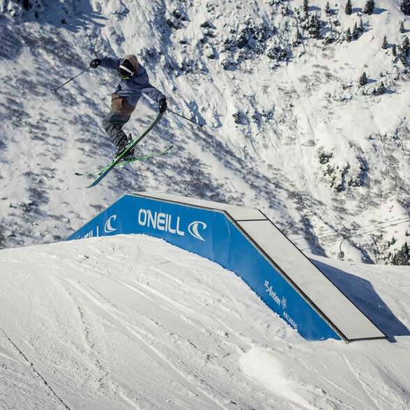 Freestyle skier jumps over a rail with “St. Anton” logo in the Arlberg snowpark.