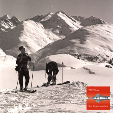Zwei Skifahrer in historischer Winteraufnahme im tief verschneiten Gebirge.