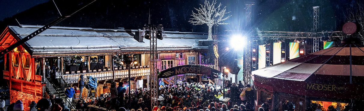 Feiernde Menschenmenge bei der Open-Air-Schlagerparty an der MooserWirt Hütte mit Live-Musik und Lichteffekten.