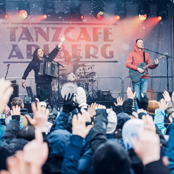 Liveauftritt mit Akkordeon und Gitarre beim Tanzcafé Arlberg Festival im Schneetreiben, vor begeistertem Publikum.