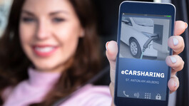 Frau hält Smartphone mit eCarsharing-App von St. Anton vor die Kamera.