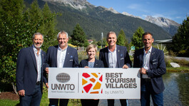 Vertreter:innen (Peter Mall, Helmut Mall, Michaela Gasser-Mark, Martin Ebster, Gerhard Eichhorn) präsentieren die Auszeichnung „Best Tourism Villages“ von UNWTO für St. Anton.
