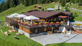 Sennhütte in St. Anton am Arlberg: traditional mountain restaurant with a large sun terrace, colorful flowers, and panoramic alpine views.