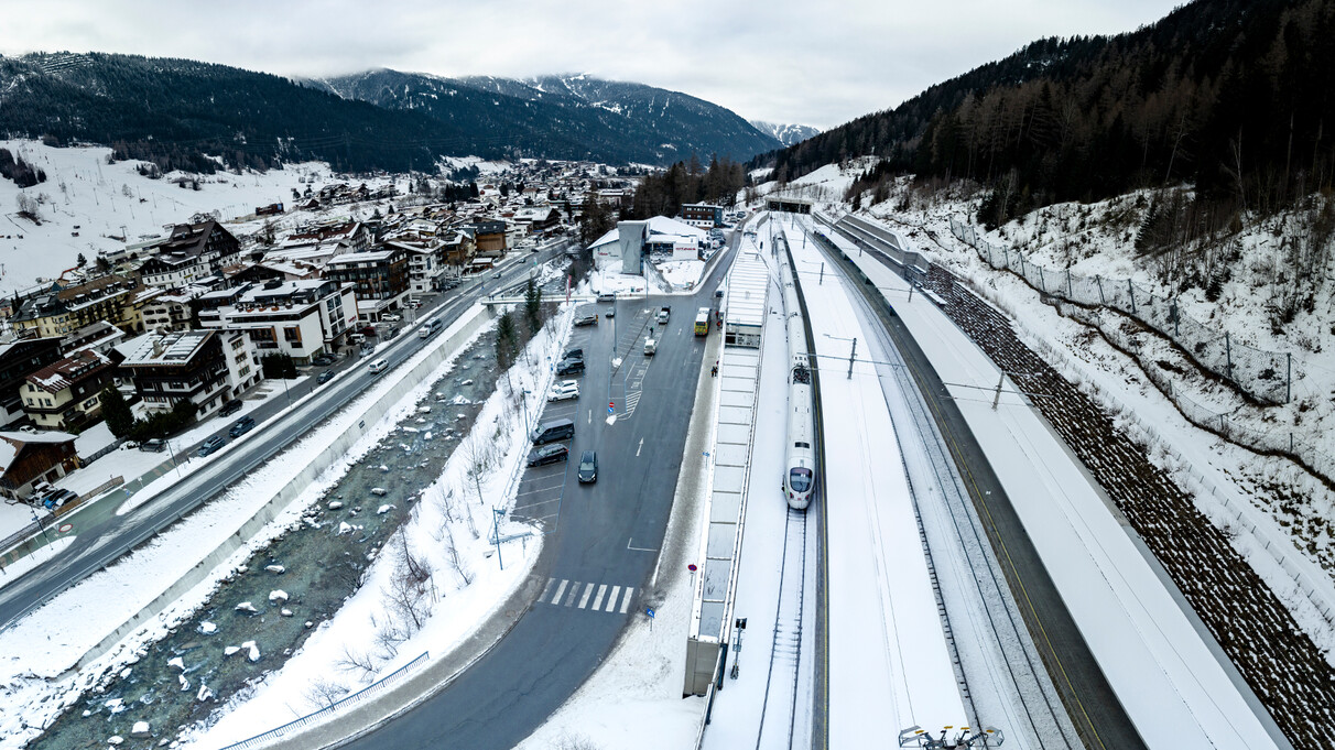 Aerial view of St. Anton station with an ICE train on snow-covered tracks and the town in the background. Eco-friendly travel on display.