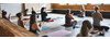 Yoga in St. Anton am Arlberg Mehrere Personen sitzen auf Yogamatten in einem Holzstudio und meditieren gemeinsam im Schneidersitz.