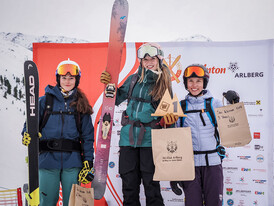 Drei junge Skifahrerinnen stehen freudestrahlend auf dem Podest der Damen U18 beim Freeride-Contest in St. Anton. Sie halten ihre Ski und Pokale vor einer Sponsorentafel.