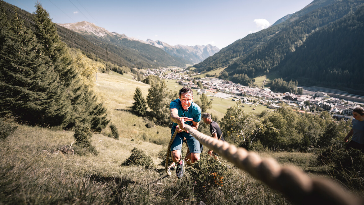 Teilnehmender beim Wadlbeißer-Wettkampf zieht sich mit Seil steil bergauf / Participant in the “Wadlbeißer” race pulls themselves uphill with a rope