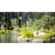 Zwei Personen entspannen auf Steinen an einem Naturteich im Sommerpark / Two people relax on stones by a natural pond in a summer park