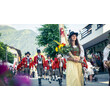Traditioneller Festumzug mit Musikanten und Frau in Tracht mit Blumen / Traditional parade with musicians and a woman in costume holding flowers