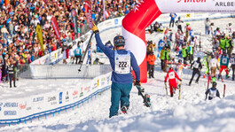 Zieleinlauf des weissen Rausch, ein Skifahrer läuft jubelnd in den Zielbereich, viele Skifahrer sind bereits im Ziel und ein tobende Menschenmasse feuert die Athleten an.