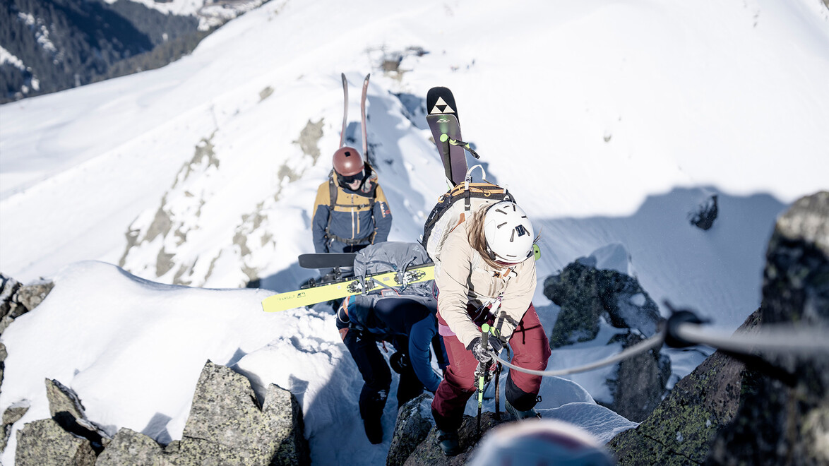 Alpinisten mit Skiern balancieren auf felsigem Schneegrat / Alpinists with skis balancing on snowy rocky ridge
