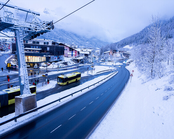 Das Terminal West in St. Anton am Arlberg zeigt einen modernen Verkehrsknotenpunkt mit gelben Linienbussen, Winterlandschaft und Gondelstation.