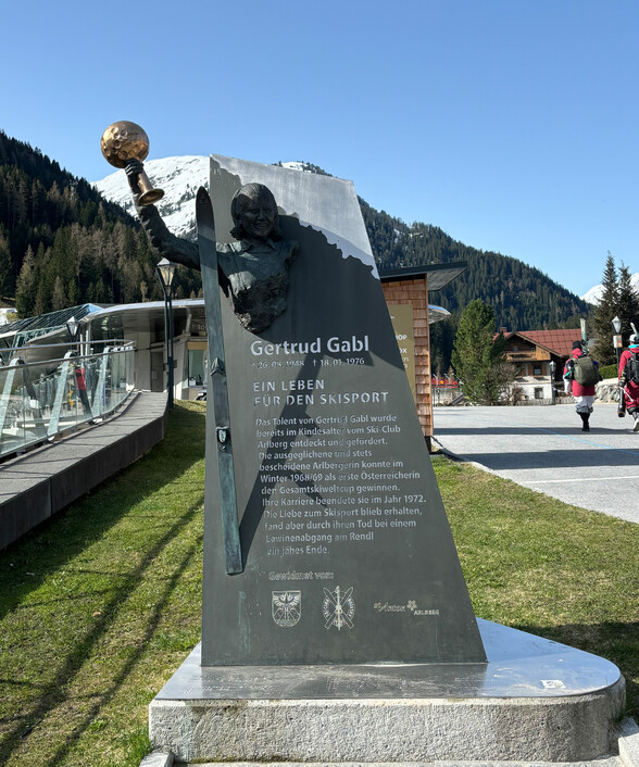 Das Denkmal für Gertrud Gabl in St. Anton zeigt ihre Statue und informiert über ihr Leben als erfolgreiche Skirennläuferin.