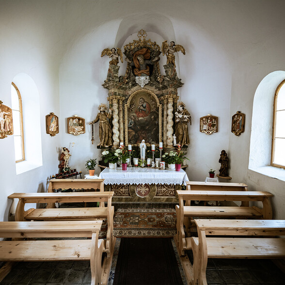 Der barocke Innenraum der Antoniuskapelle in Flirsch mit Altar, Heiligenfiguren und schlichtem Gebetsraum aus Holz.