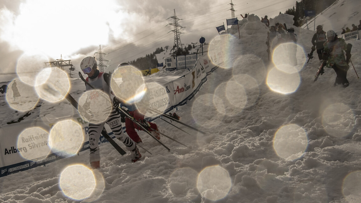 Sportler kämpfen sich mit Skiern durch Schnee bei schlechter Sicht und Lichtreflexen / Athletes push through snow with skis in low visibility and light reflections