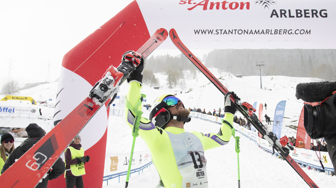 Sieger hebt Skier im Zieltor über dem Kopf triumphierend in die Luft / Winner lifts skis over head triumphantly at the finish gate