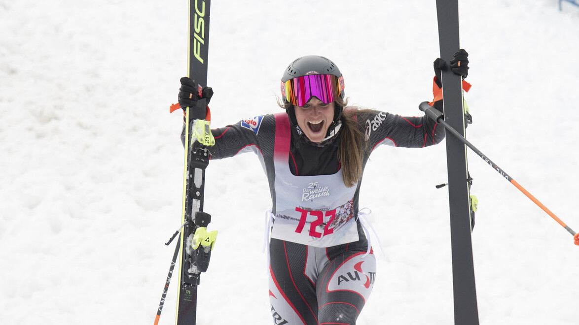 Athletin mit Startnummer und Helm erreicht freudestrahlend das Ziel / Athlete with bib and helmet reaches the finish with joy