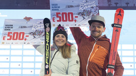Regina Wintersteller und Dieter Bischof jubeln mit ihren Siegerpreisen auf der Bühne vor einer Wand voller Sponsorenlogos