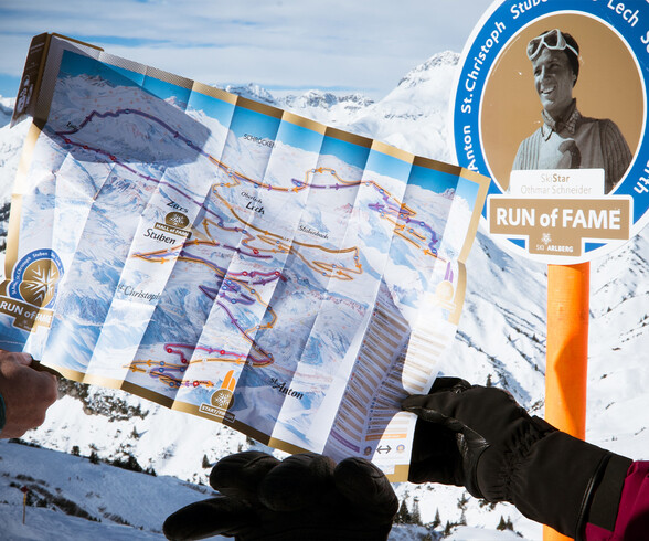 Winterliche Übersichtskarte des Run of Fame vor einer Tafel mit Othmar Schneider im Skigebiet