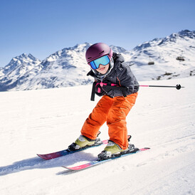 Kind auf Skiern in der Hocke unterwegs auf den Pisten St. Anton am Arlberg