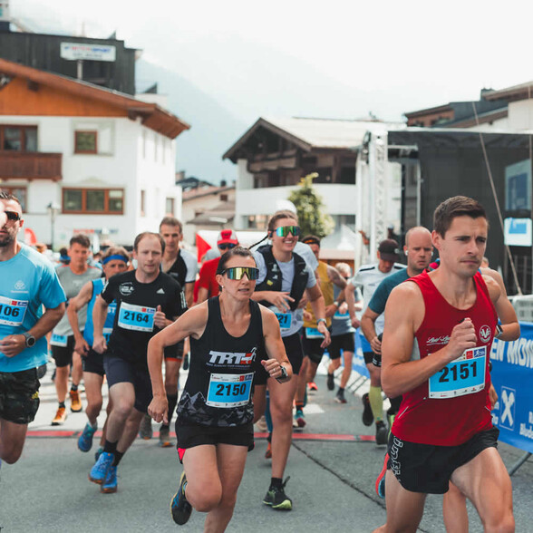 Der Arlberg Marathon 2024 beginnt: Zahlreiche Läuferinnen und Läufer starten dynamisch im Ortszentrum von St. Anton am Arlberg.