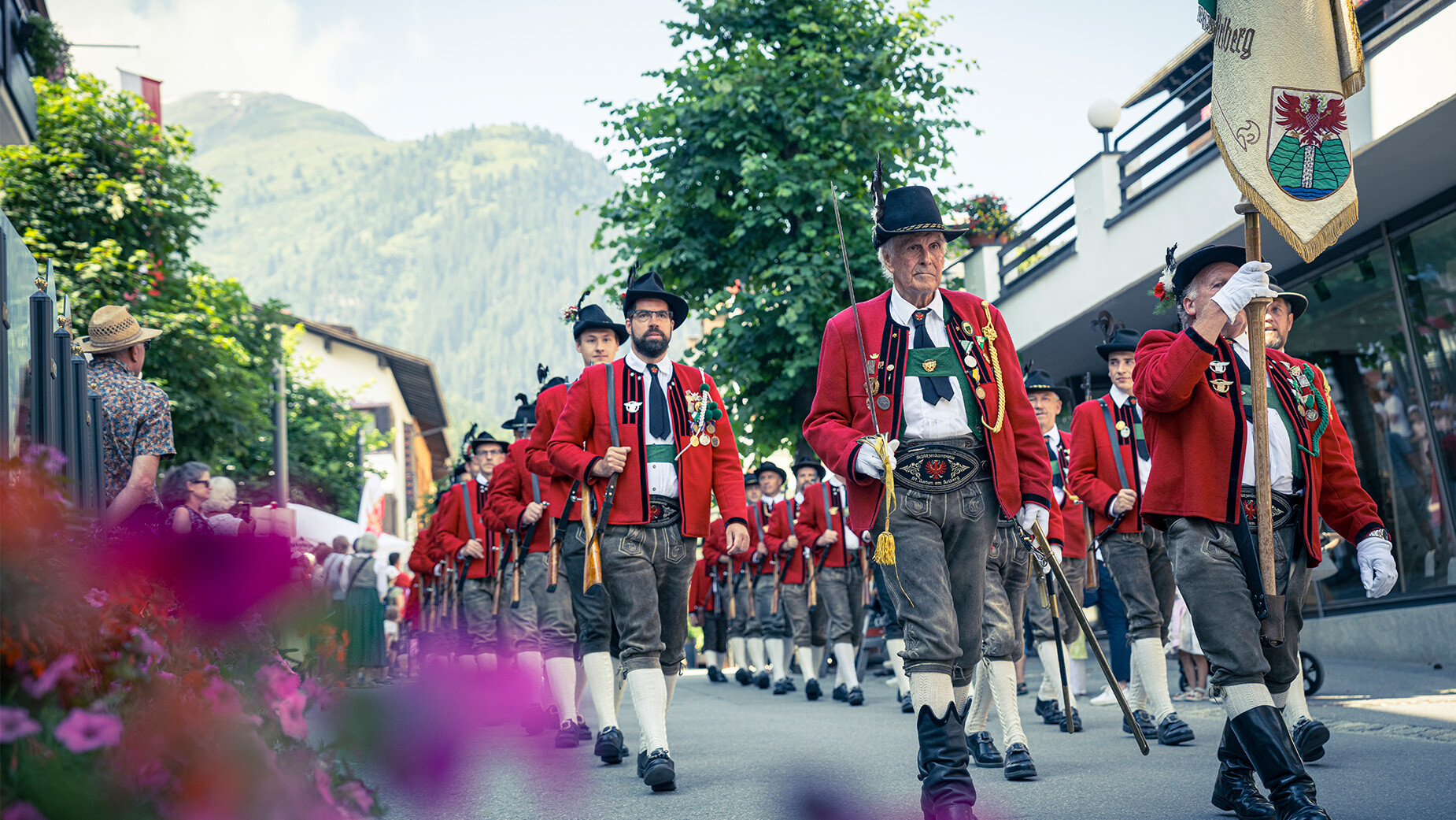 Schützenkompanie in roten Uniformen marschiert mit Gewehren beim Umzug / Riflemen company in red uniforms marches with rifles in a parade