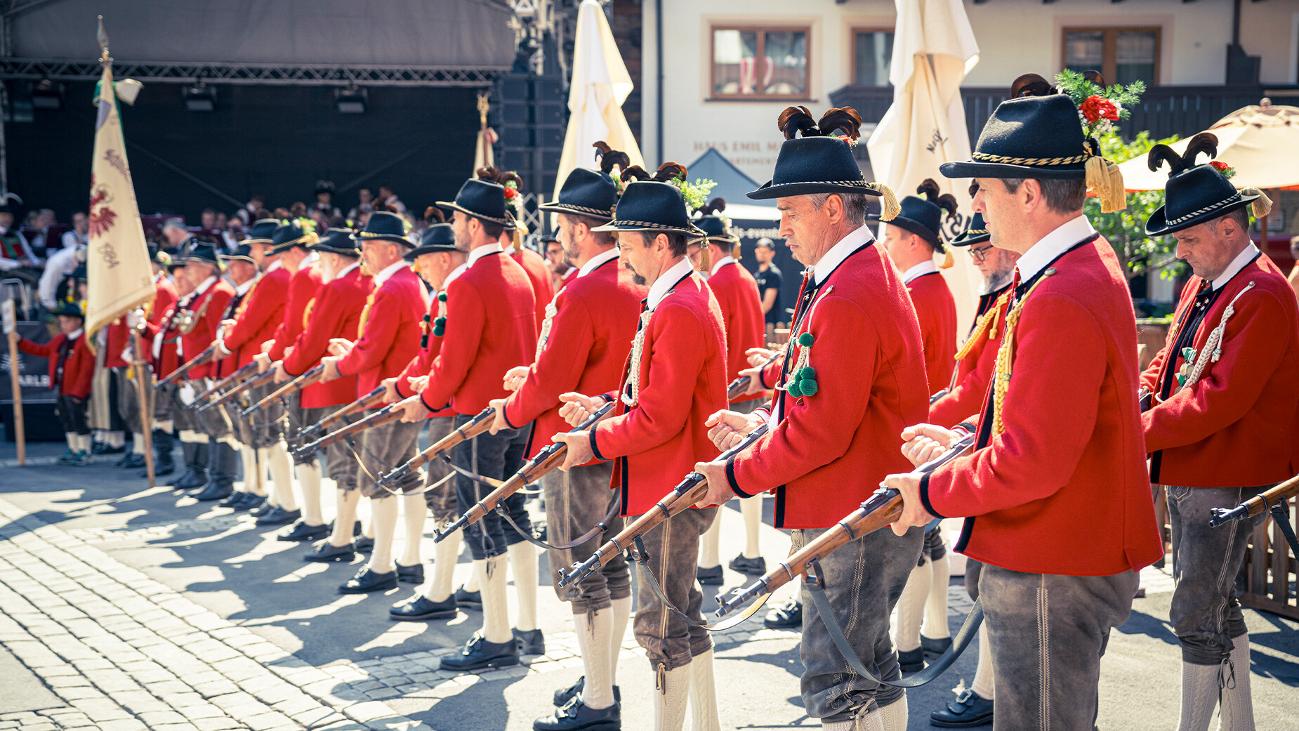 Reihe von Musikanten in roter Uniform mit Blasinstrumenten beim traditionellen Auftritt / Row of musicians in red uniforms with brass instruments during a traditional performance