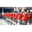 Reihe von Musikanten in roter Uniform mit Blasinstrumenten beim traditionellen Auftritt / Row of musicians in red uniforms with brass instruments during a traditional performance