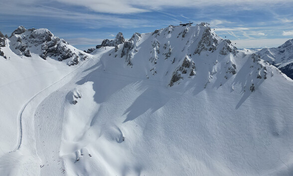 Schneebedeckte Gipfel und steile Felsformationen rund um den Schindlergrat bei sonnigem Himmel.