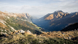 Panoramablick auf das herbstliche Stanzertal mit farbigen Hängen und Berggipfeln.