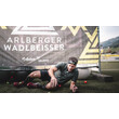 Ein Sportler kriecht lachend unter einem Netz mit dem Logo des Events im Hintergrund. / An athlete crawls laughing under a net with the event logo in the background.