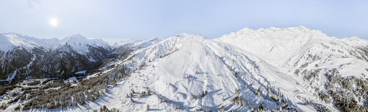 Panoramaaufnahme des schneebedeckten Skigebiets am Galzig mit weiten Pisten, bewaldeten Hängen und Alpen im Hintergrund.