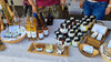 Vielfältiges Angebot an Marmeladen, Honig, Sirup und Naturkosmetik auf einem Marktstand. / Wide range of jams, honey, syrup and natural cosmetics at a market stall.