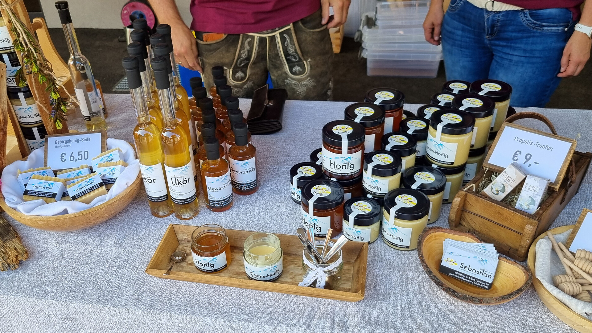 Vielfältiges Angebot an Marmeladen, Honig, Sirup und Naturkosmetik auf einem Marktstand. / Wide range of jams, honey, syrup and natural cosmetics at a market stall.