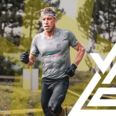 Participant in the Arlberger Wadlbeisser Run 2025 runs through a muddy track in the forest, dressed in sportswear.