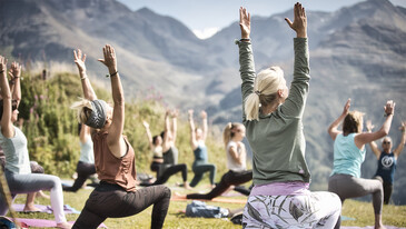 A group practices outdoor yoga with mountain views – mindfulness meets alpine nature.