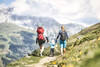 Wandern mit Familie / Family Hiking Familie wandert gemeinsam einen alpinen Weg mit blühenden Wiesen und Bergkulisse / Family hikes along an alpine trail with blooming meadows and mountain scenery
