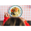 Eine Person isst auf kariertem Tischtuch ein traditionelles Gericht mit Knödeln und Soße / A person enjoys a traditional dish with dumplings and sauce on a checkered tablecloth