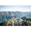 Gruppe steht am Gipfel mit Panorama auf Berglandschaft und Tal von St. Anton am Arlberg / Group stands on a summit with panoramic views of the mountain landscape and St. Anton valley
