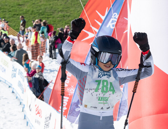 Nachwuchsfahrer Xaver jubelt im Ziel des Weissen Rausch Mini-Rennens mit erhobenen Armen.