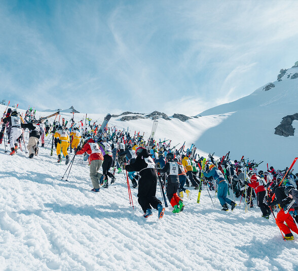 Skifahrer kämpfen sich mit Skiern in den Händen den Anstieg hinauf