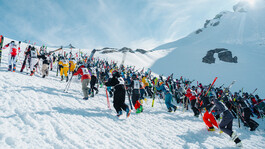 Skifahrer kämpfen sich mit Skiern in den Händen den Anstieg hinauf