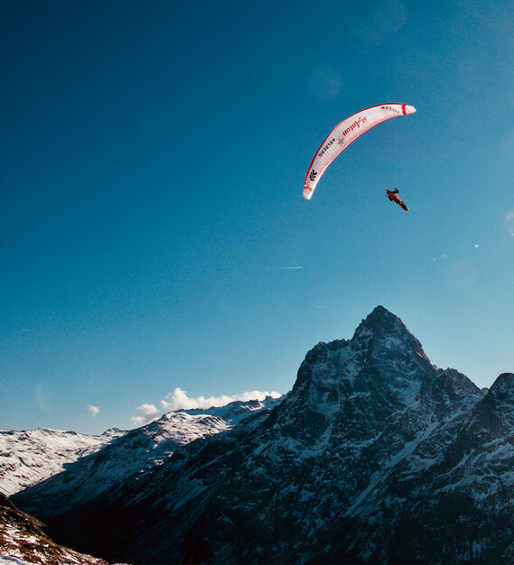 Simon Raffeiner im Gleitflug über den verschneiten Patteriol im Winter