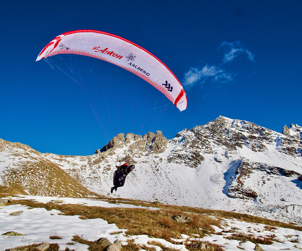 Simon Raffeiner bei einem Start auf einem Berg mit seinem weiß-roten Paragleitschirm