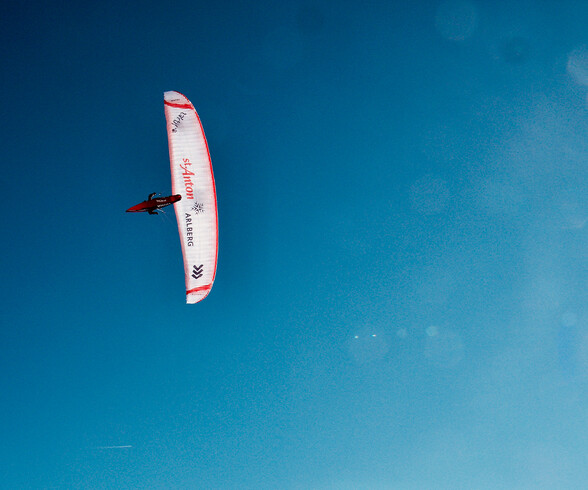 Paragleitflug von unten, Simon Raffeiners Gleitschurm ist von unten vor blauem Himmel zu sehen
