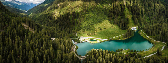 The crystal blue Verwallsee in the middle of the dense, green forest in the Verwall near St. Anton am Arlberg