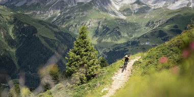 A mountain biker rides the challenging Rendl trail, with great views of the Galzig in the north.