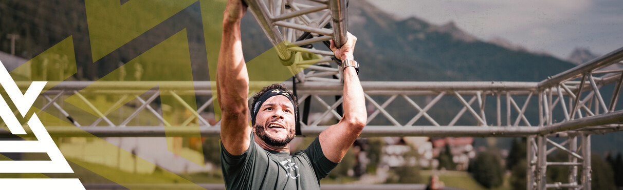 Man hängelt sich mit dem dem Armen an Eisenstangen entlang beim Arlberger Wadlbeisser. Links ist das Logo in weiß des Laufes als Stilmittel eingebaut.