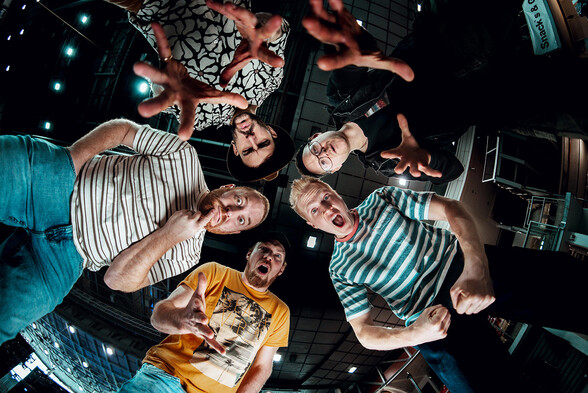 Band Fäaschtbänkler bestehend aus 5 Männern die stehend von oben auf die am Boden liegende Kamera schauen.