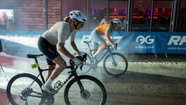 Zwei Radfahrerinnen beim Night Sprint durch die nasse, dunkle Fußgängerzone von St. Anton von der Seite abgelichtet.